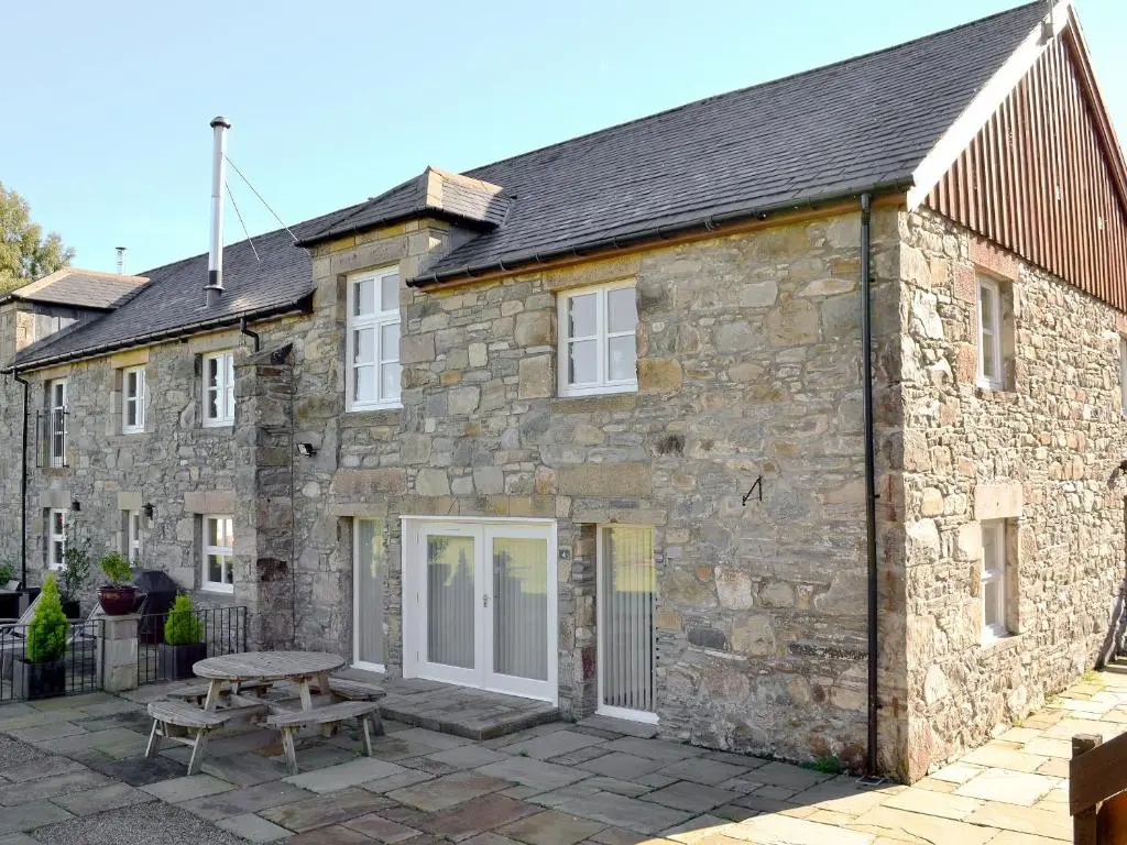 a stone house with a picnic table in front of it at The Old Granary in Ballindalloch
