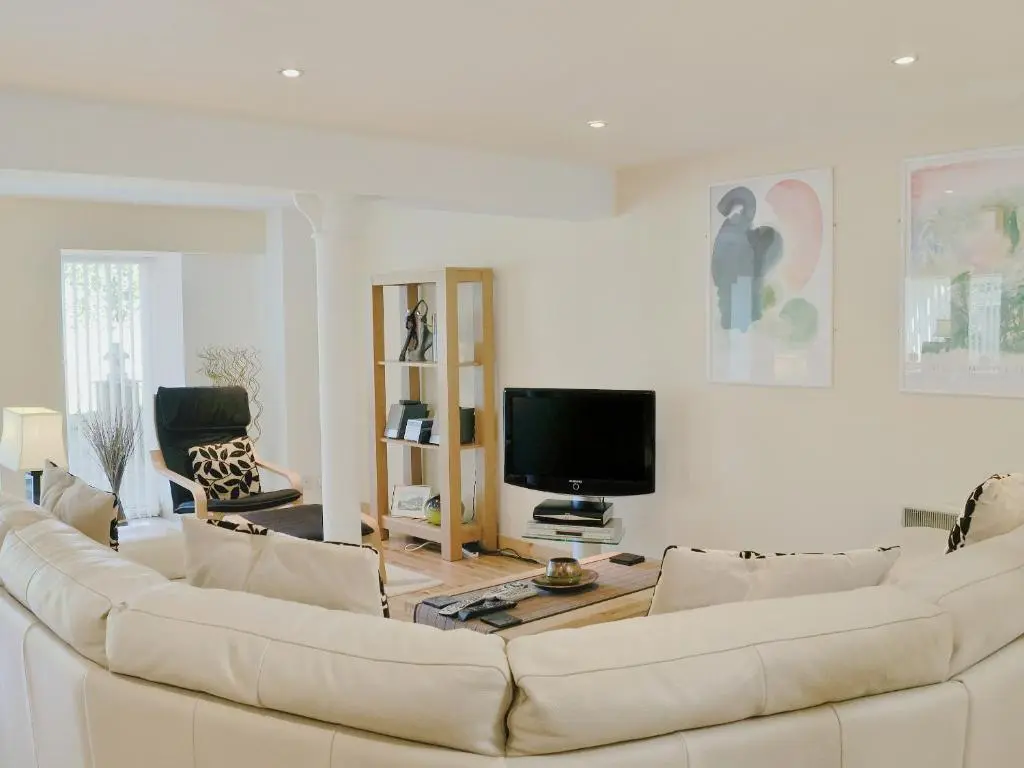 a living room with a white couch and a flat screen tv at The Old Granary in Ballindalloch