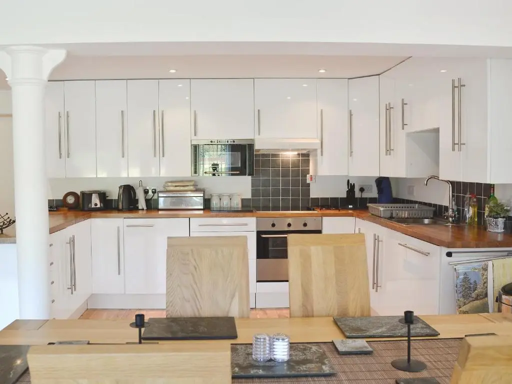 a kitchen with white cabinets and a table with chairs at The Old Granary in Ballindalloch