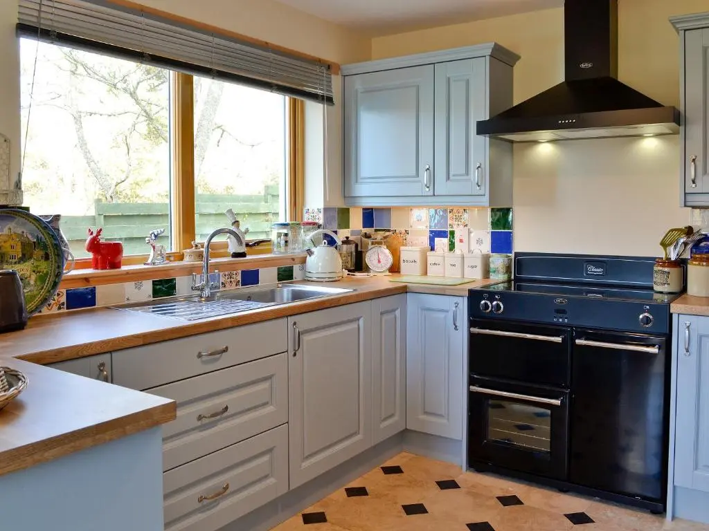 a kitchen with white cabinets and black appliances at Mountain View in Tomintoul