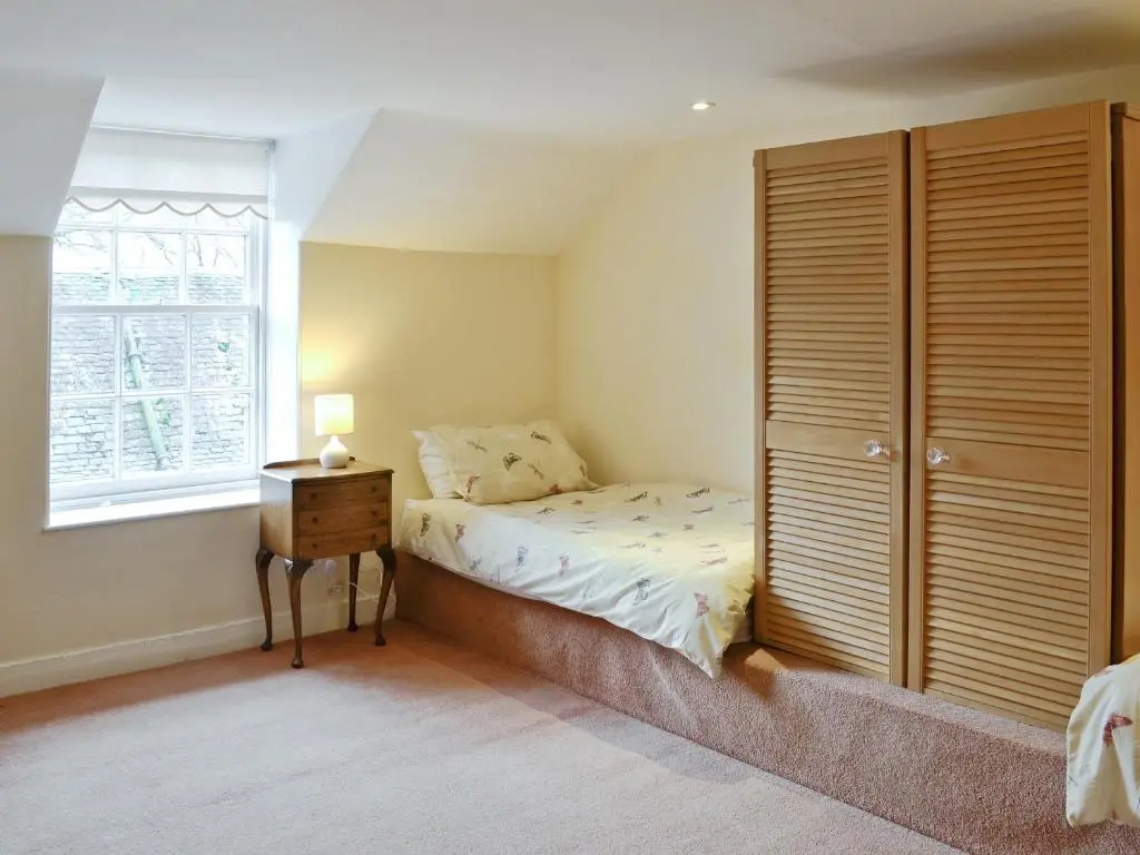 a bedroom with a bed and a dresser and a window at The Mews in Insch