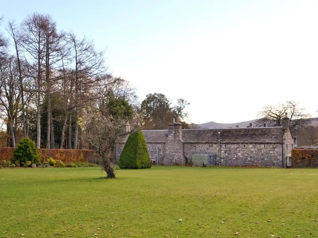 an old stone building in a field with a tree at The Mews in Insch