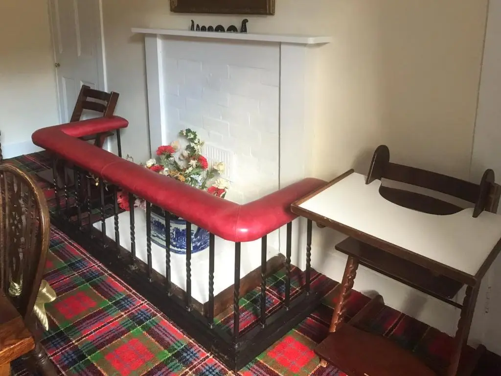 a living room with a table and a red bench at The Mews in Insch