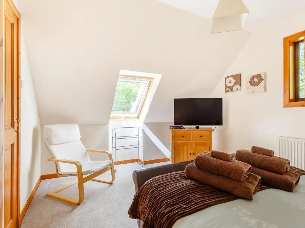 a room with a bed and a chair and a television at Glen View Of Enrick House in Bearnock