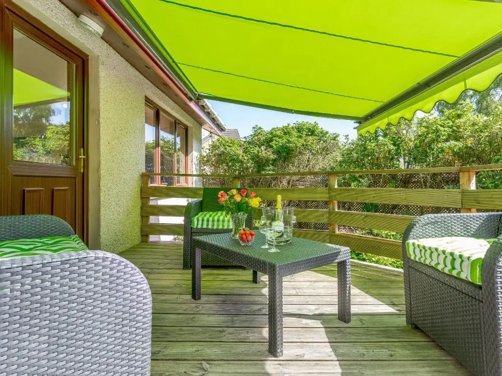a porch with chairs and a table with flowers on it at Glen View Of Enrick House in Bearnock