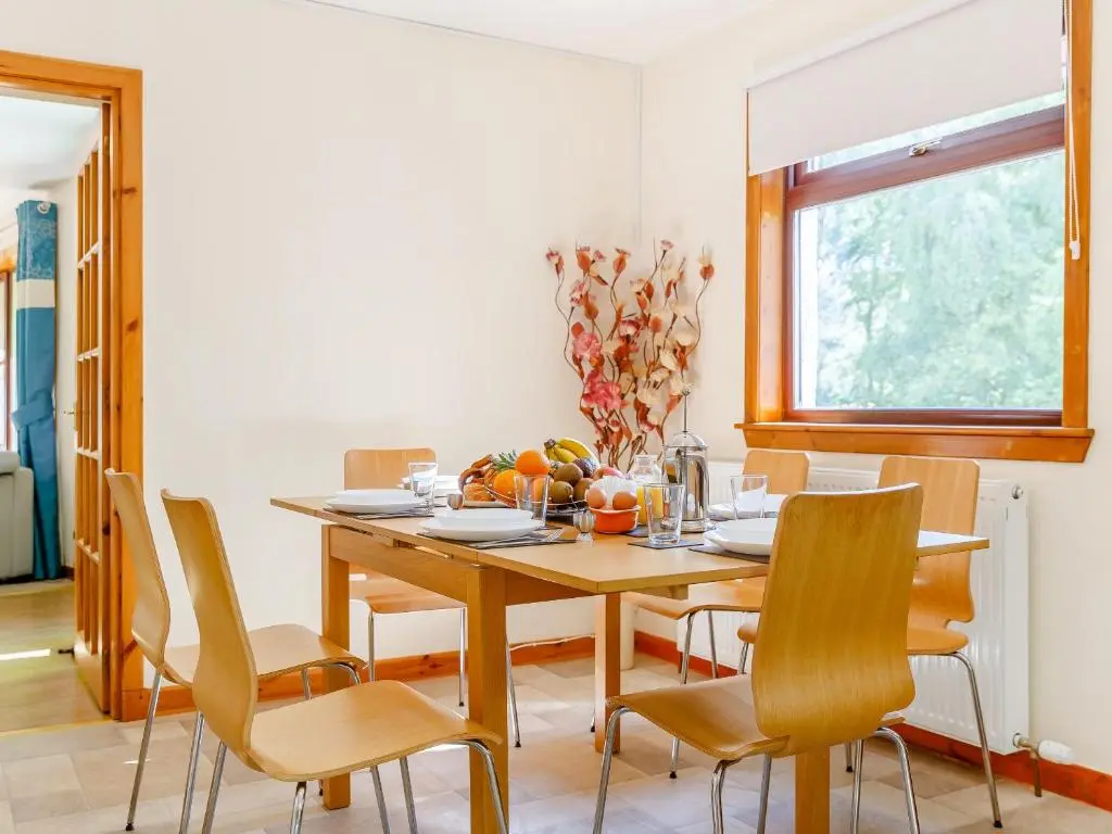 a dining room with a wooden table and chairs at Glen View Of Enrick House in Bearnock