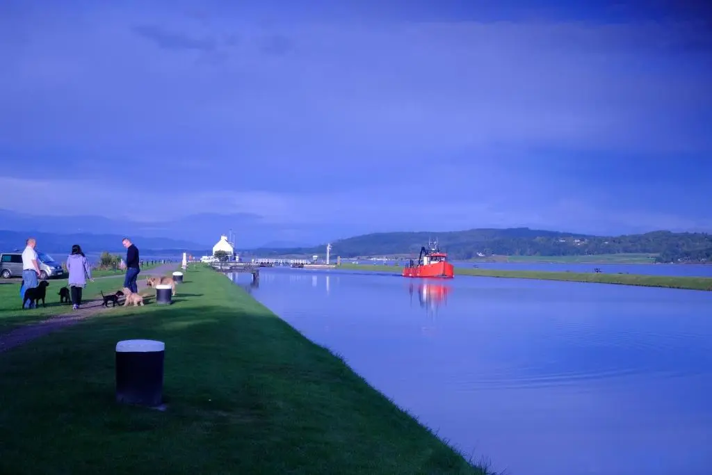 a group of people standing next to a body of water at Otter Cottage in Inverness