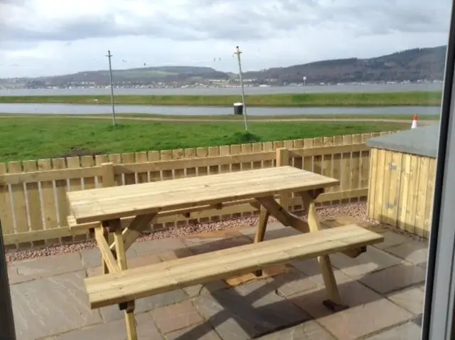 a wooden bench sitting on top of a patio at Otter Cottage in Inverness