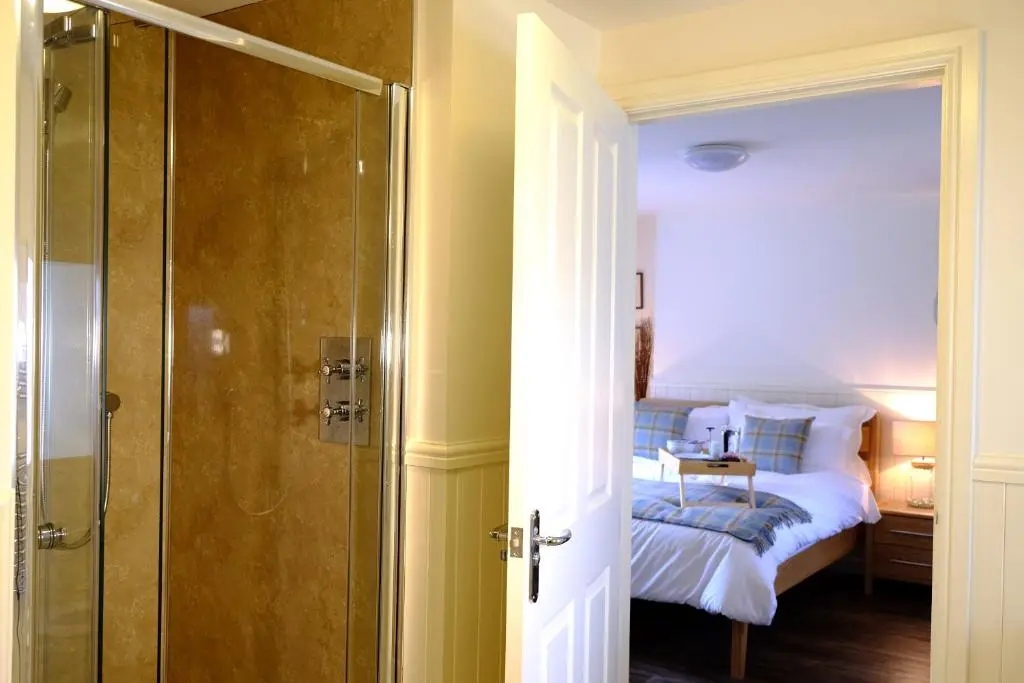 a bedroom with a bed and a glass shower at Otter Cottage in Inverness