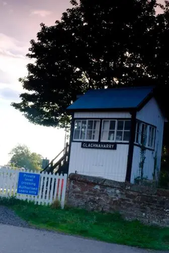 a small white building with a fence next to a tree at Otter Cottage in Inverness