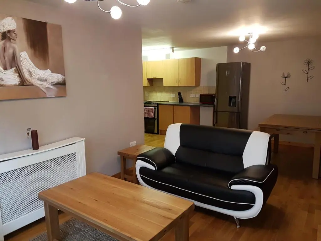 a living room with a black leather couch and a table at Lascala City Apartment in Inverness