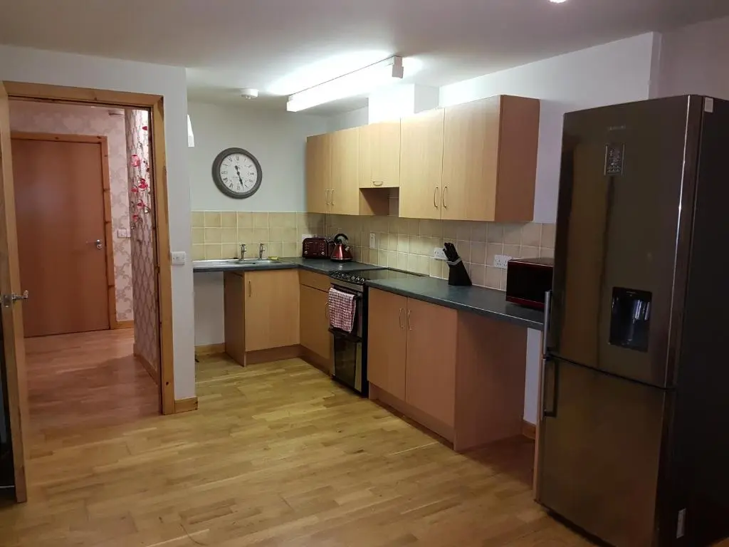 a kitchen with a refrigerator and a clock on the wall at Lascala City Apartment in Inverness