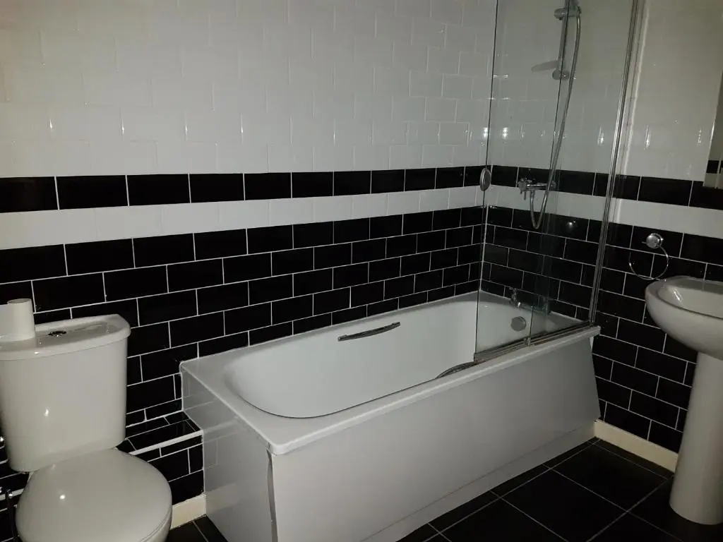a bathroom with a tub and a toilet and a sink at Lascala City Apartment in Inverness