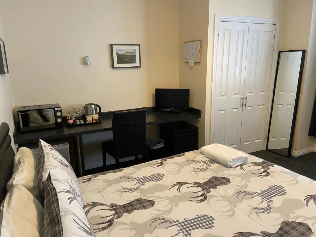 a bedroom with a bed and a desk with a computer at Ivy Cottage-Serviced accommodation in Dyce