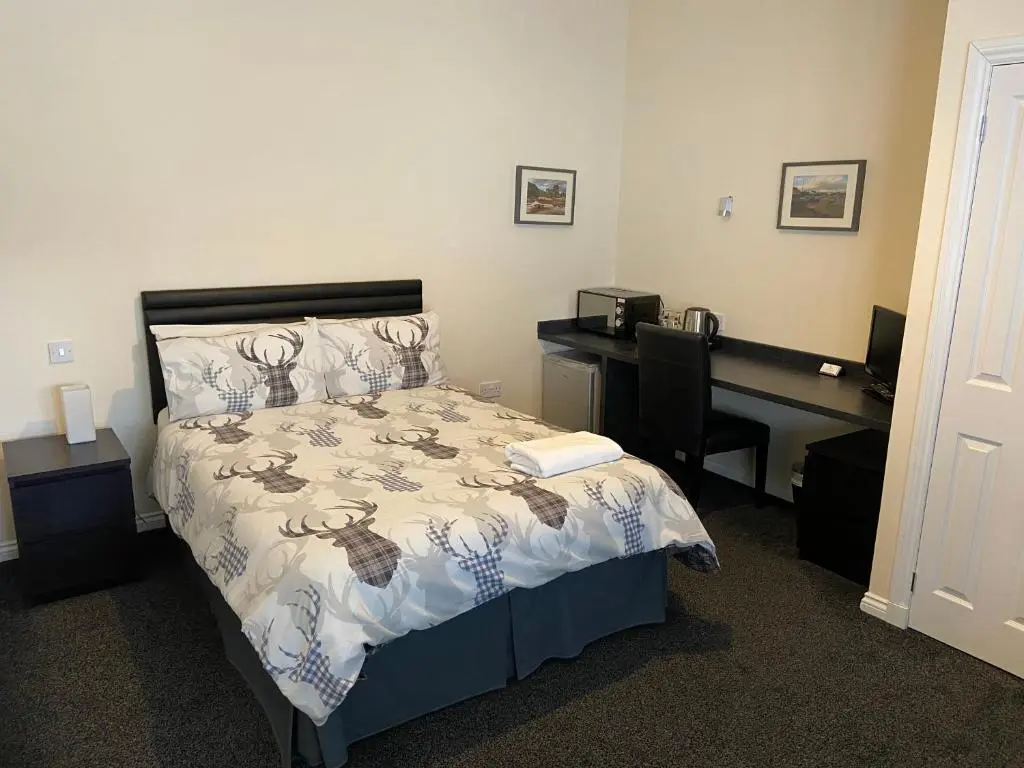 a bedroom with a bed and a desk with a computer at Ivy Cottage-Serviced accommodation in Dyce
