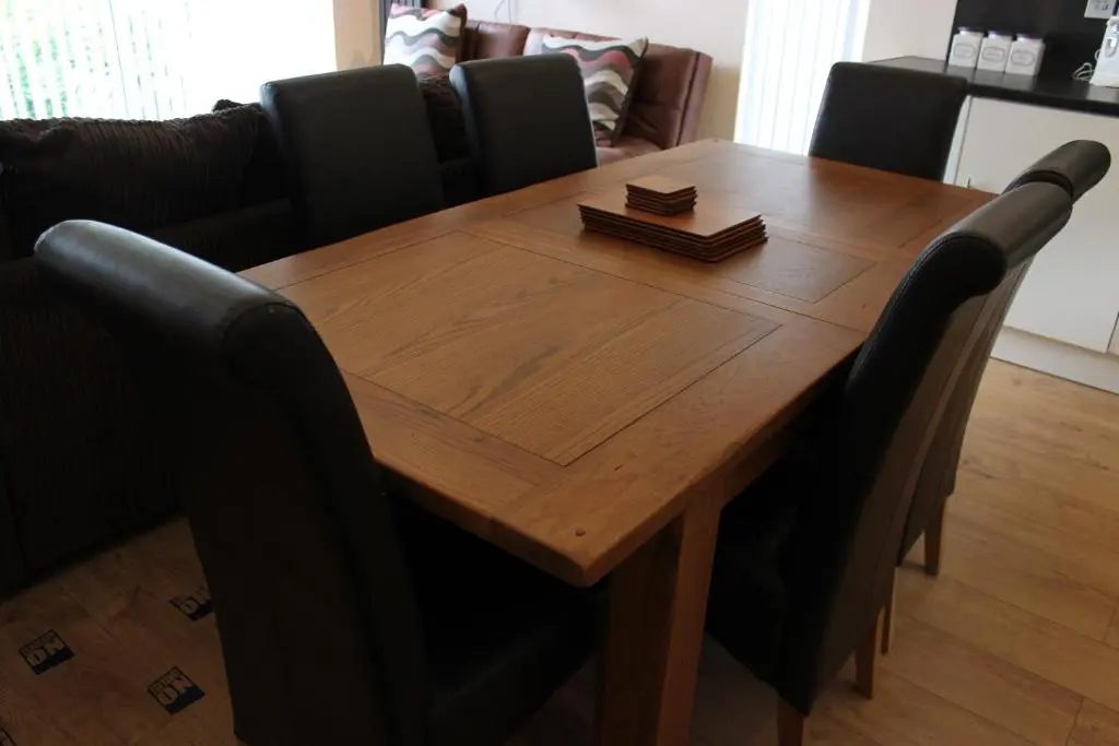 a wooden table with black chairs around it at Loch Ness Highland Cottages with partial Loch View in Invermoriston