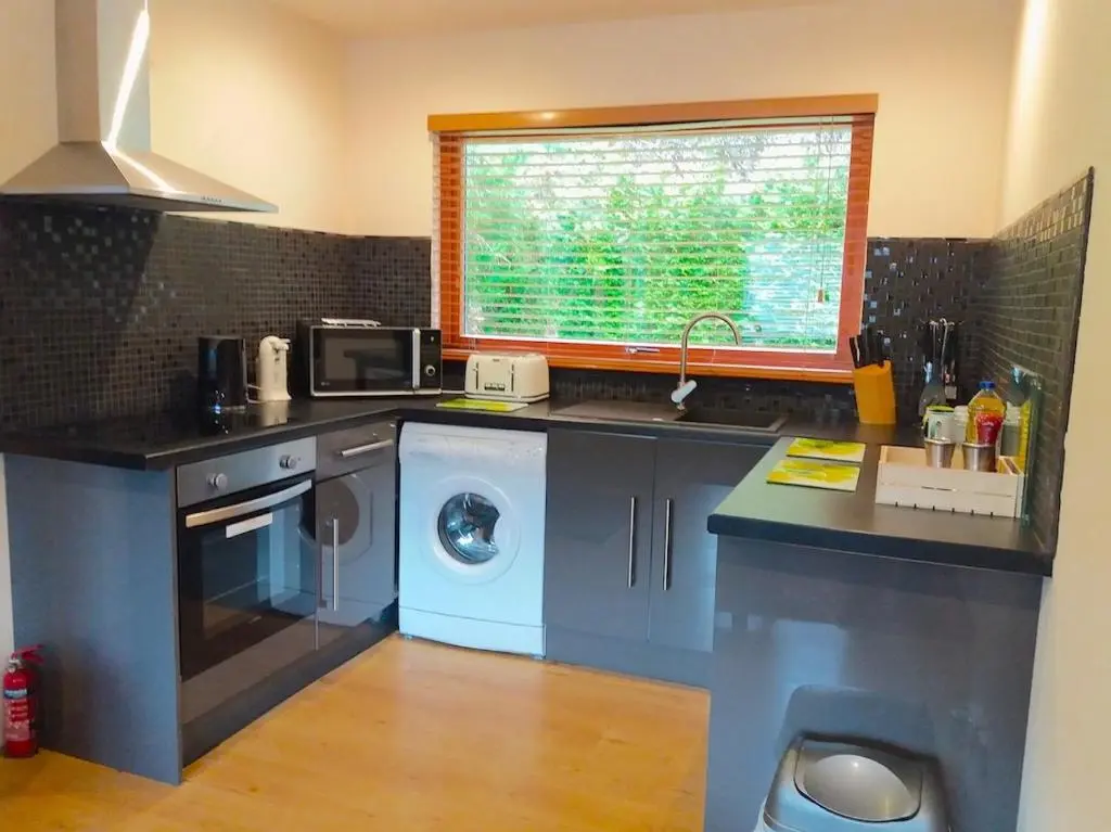 a kitchen with a sink and a washing machine at Loch Ness Highland Cottages with partial Loch View in Invermoriston