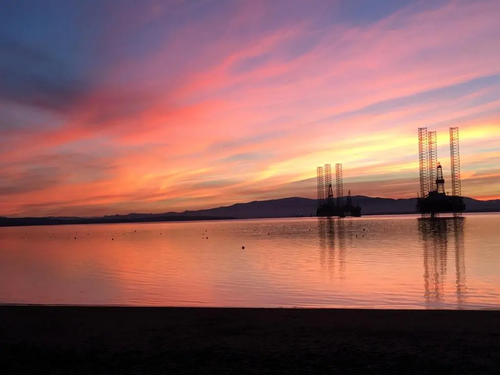 a sunset over a large body of water with towers at The Royal Hotel Cromarty in Cromarty