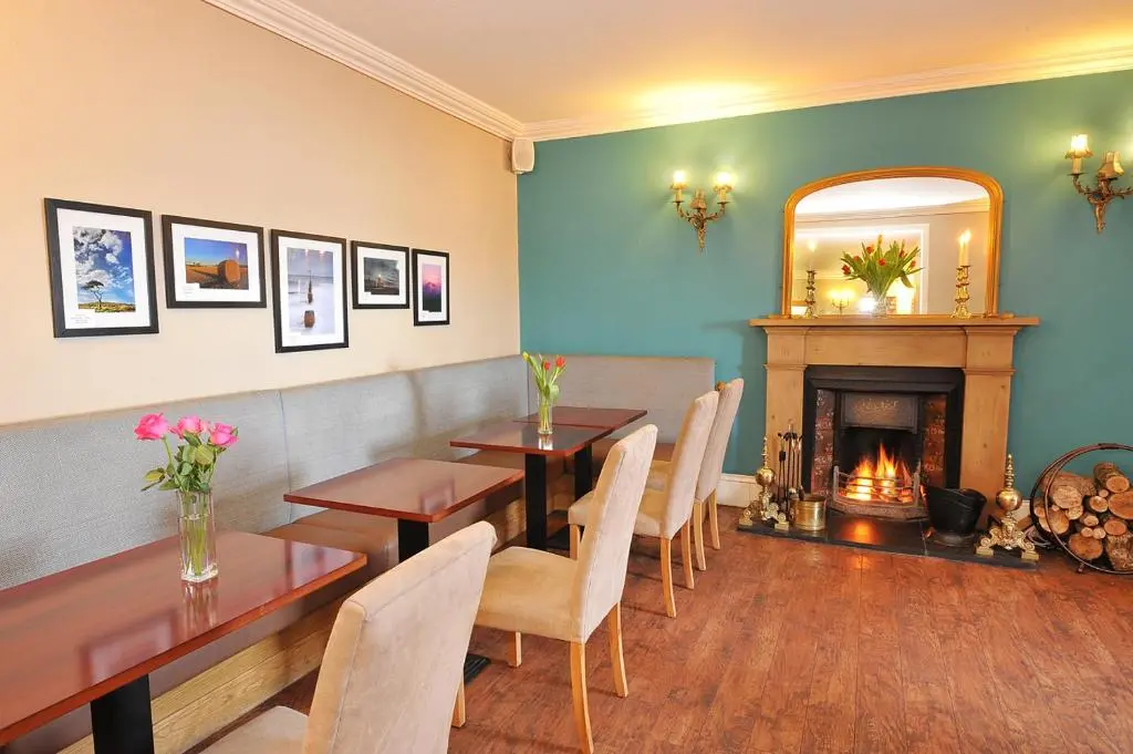 a dining room with a table and a fireplace at The Royal Hotel Cromarty in Cromarty