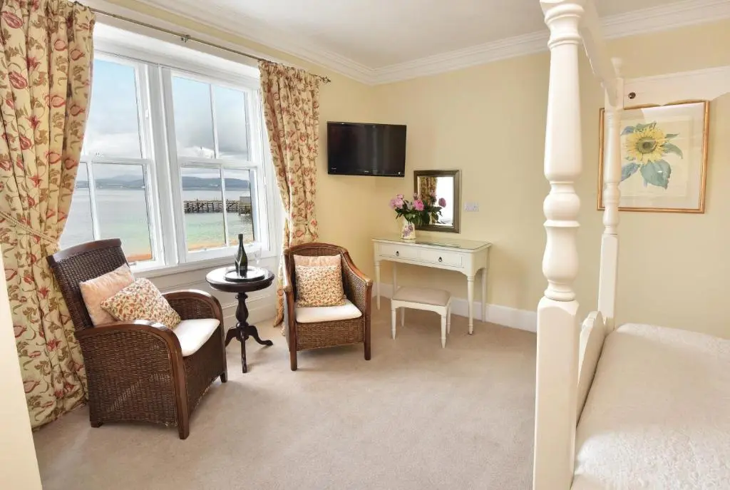 a bedroom with a bed and chairs and a window at The Royal Hotel Cromarty in Cromarty
