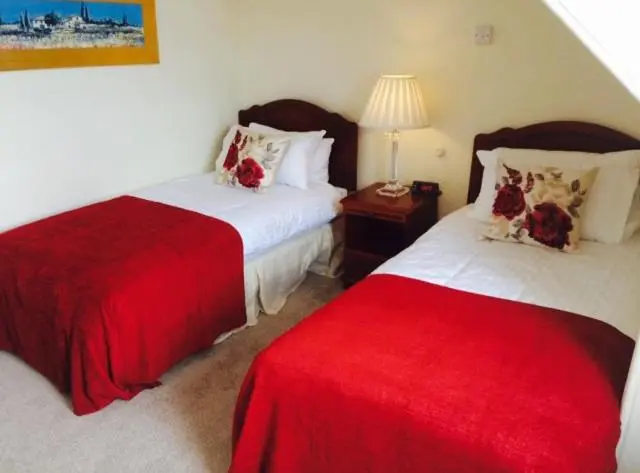 two beds in a room with red and white at The Royal Hotel Cromarty in Cromarty