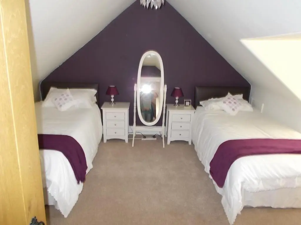 a attic bedroom with two beds and a mirror at Inveravon Holiday Home in Dufftown
