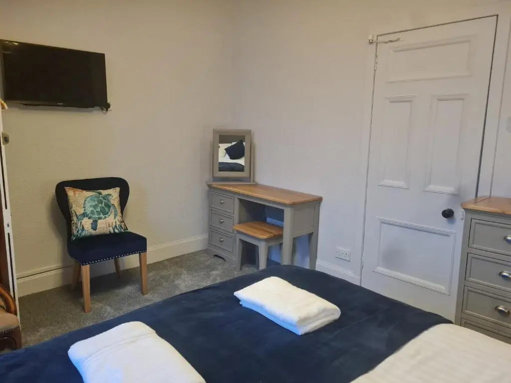 a bedroom with a bed and a desk and a chair at Victoria Hotel in Portknockie