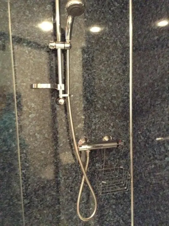 a shower with a shower head and a glass door at North End The Cottage in Nairn