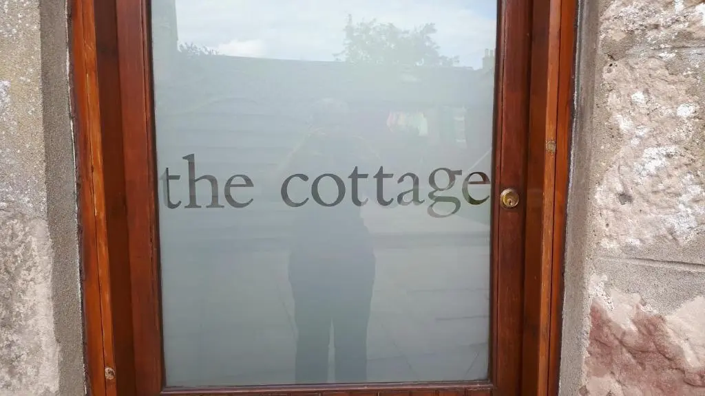 a glass door with the coffee sign on it at North End The Cottage in Nairn