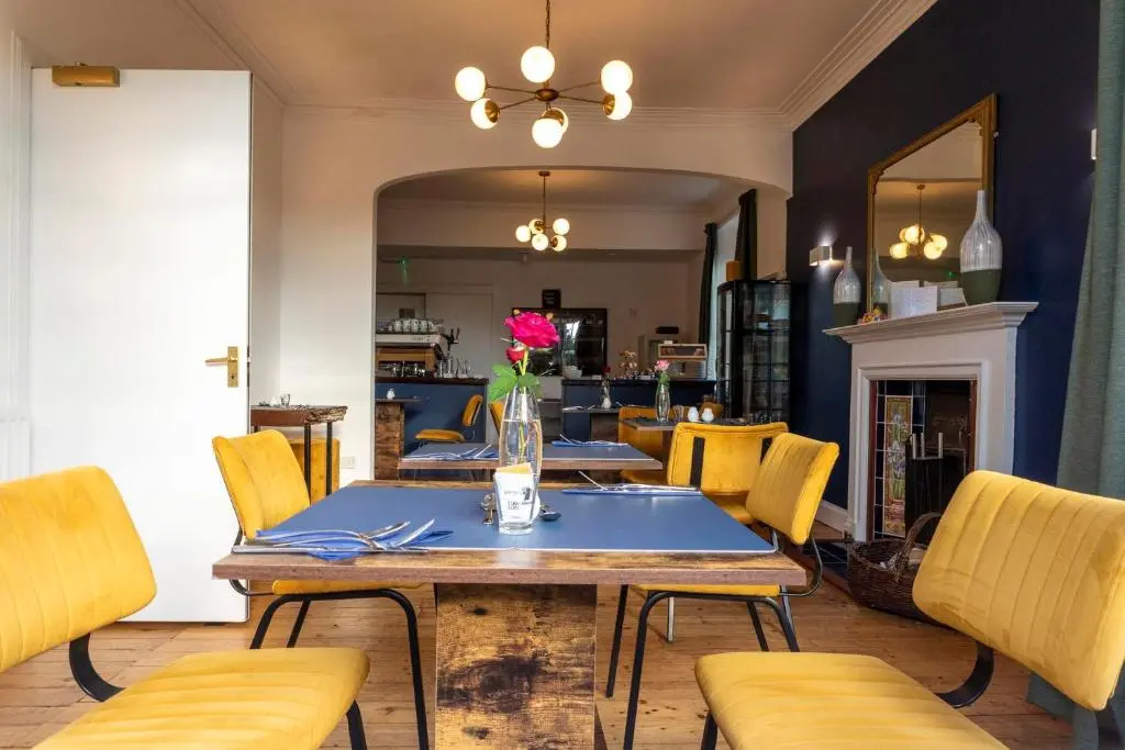 a dining room with a table and yellow chairs at Cawdor House B&B in Nairn