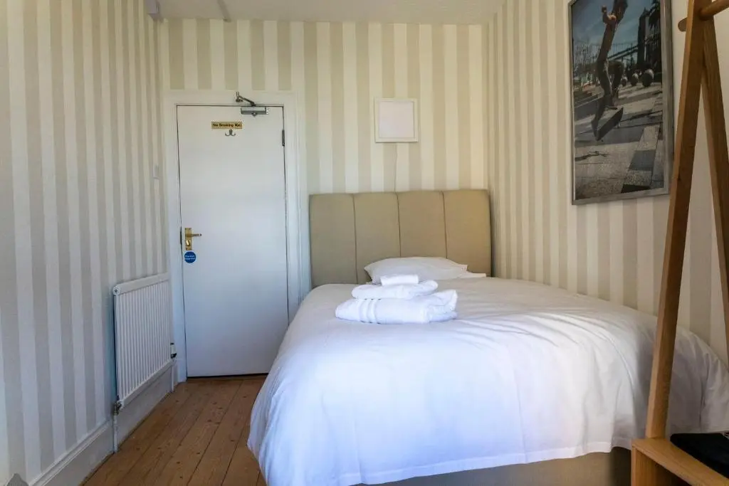 a bedroom with a white bed with towels on it at Cawdor House B&B in Nairn