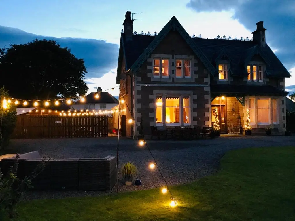 a house with lights in the yard at night at Lairds Lodge Inverness in Inverness
