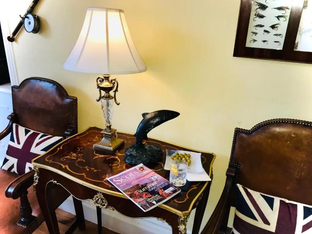 a table with a lamp on it with two chairs at Lairds Lodge Inverness in Inverness
