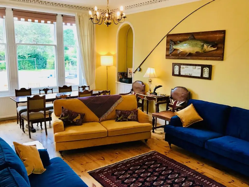 a living room with a blue couch and a dining room at Lairds Lodge Inverness in Inverness