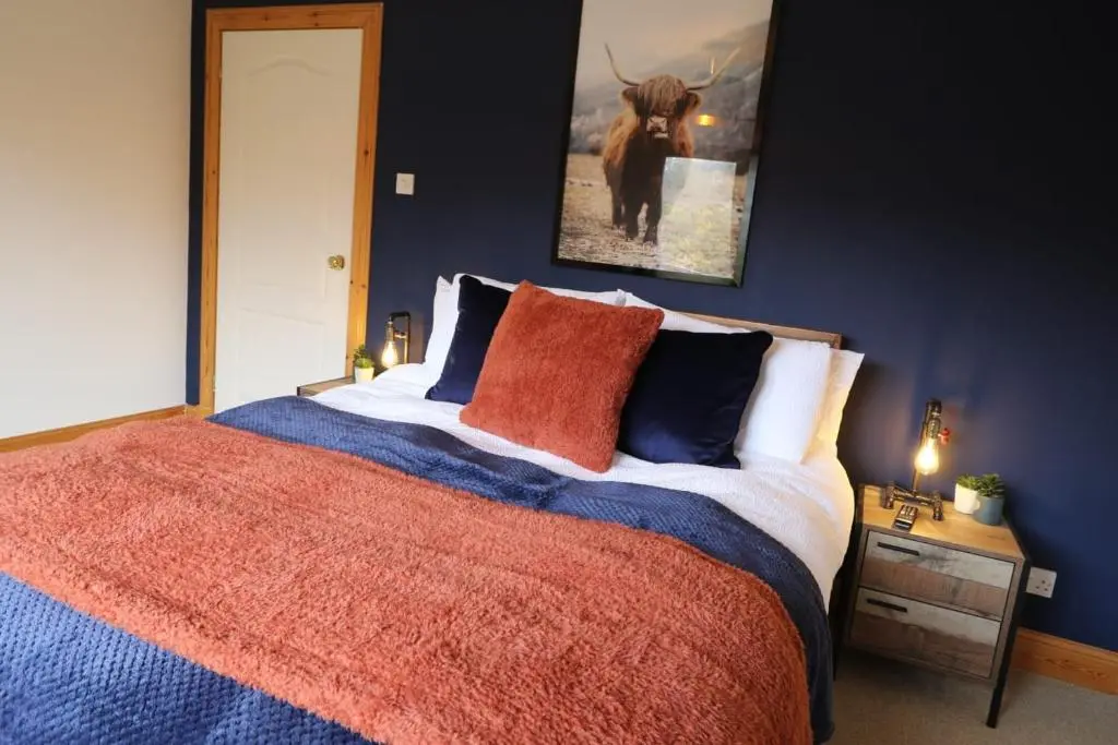 a bedroom with a large bed with blue walls at Acarsaid B&B in Lybster