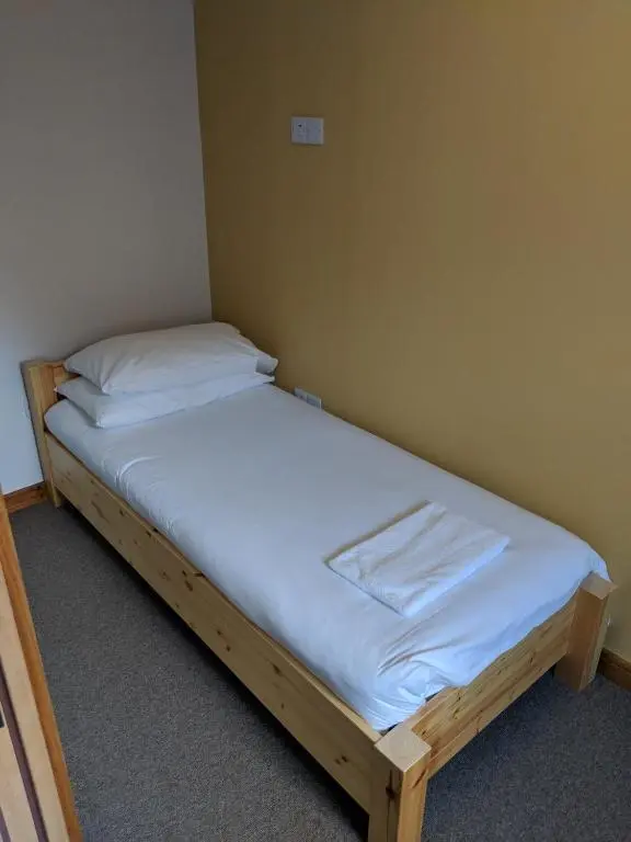 a bed in a small room with a white mattress at Black Isle Bar & Rooms in Inverness