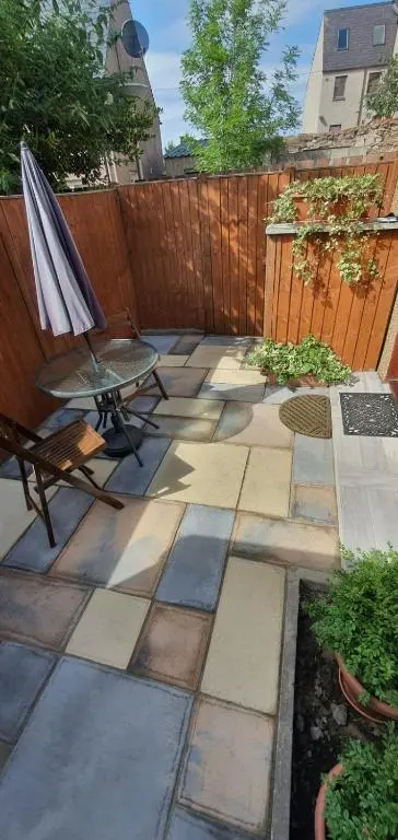 a patio with a table and an umbrella and a chair at Cosy Ness Escape, 16B Ardconnel Street in Inverness