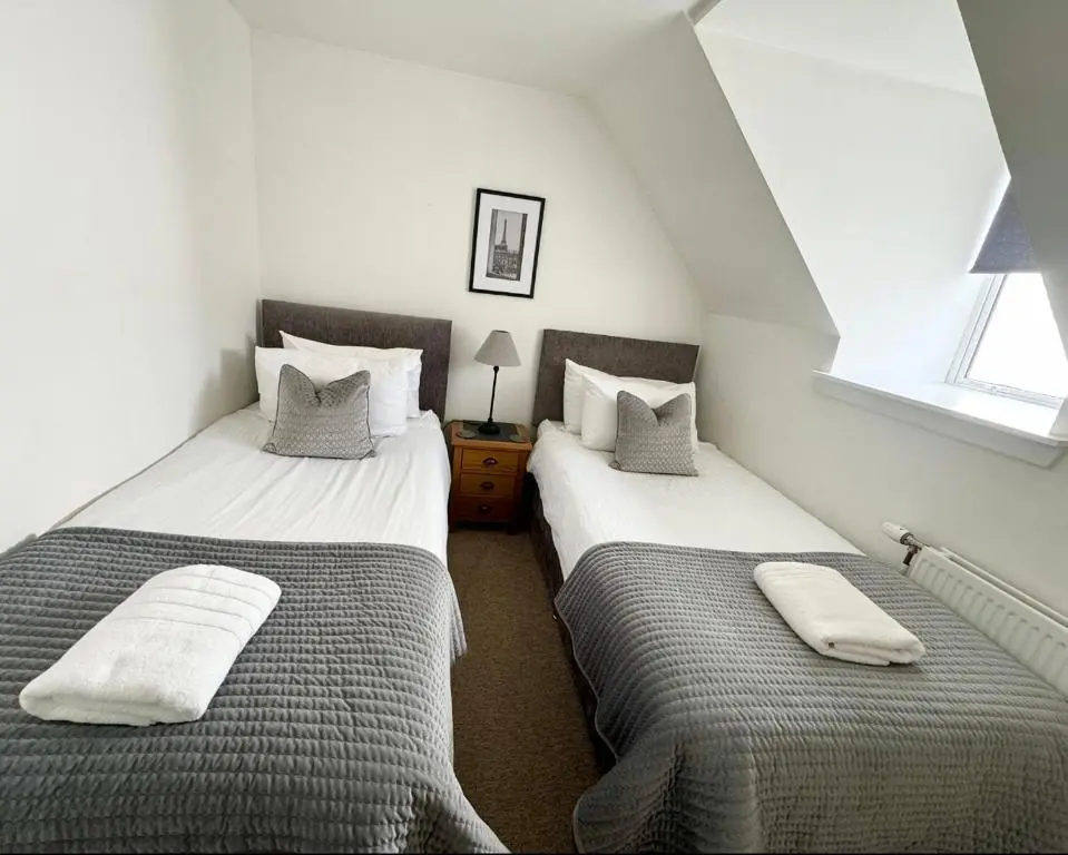 two twin beds in a attic room withskirts at City Centre Cottage in Inverness