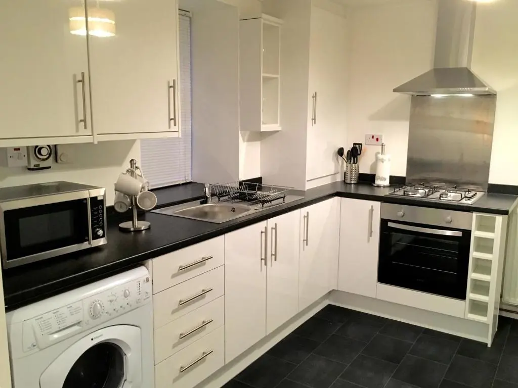 a kitchen with white cabinets and a sink and a dishwasher at City Centre Cottage in Inverness
