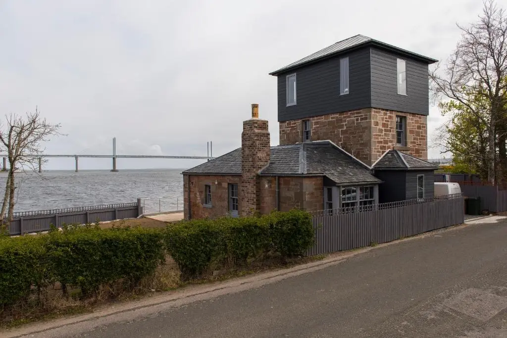 a house on the side of a road next to the water at Tangle Tower in Inverness