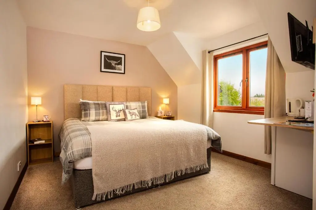 a bedroom with a large bed and a window at Beechwood Lodge in Alness