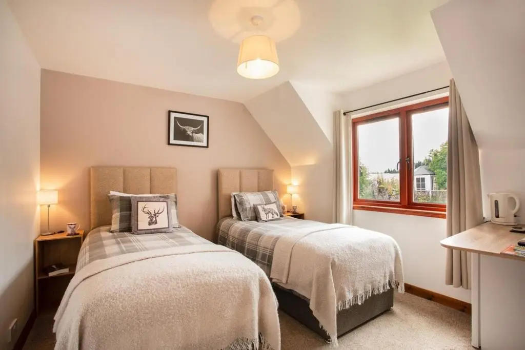 two beds in a room with a window at Beechwood Lodge in Alness