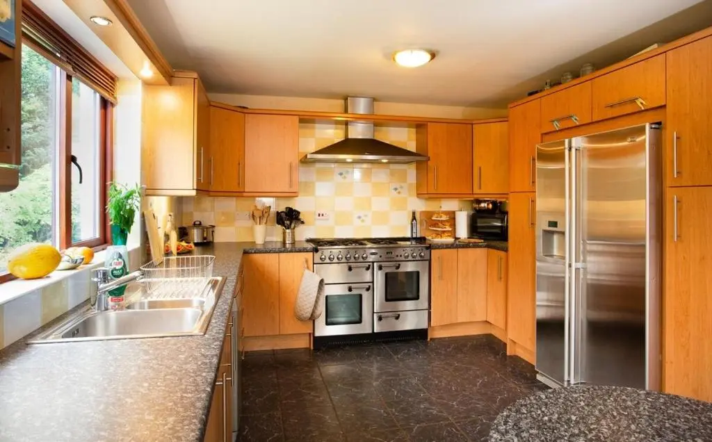 a kitchen with wooden cabinets and a stainless steel refrigerator at Beechwood Lodge in Alness