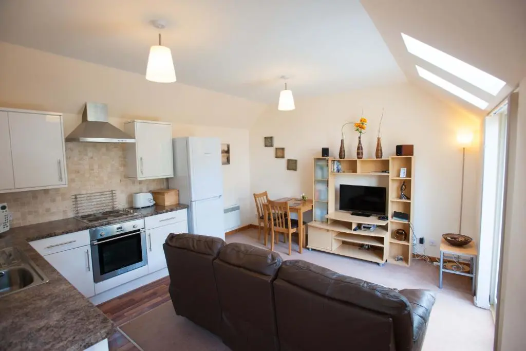 a living room with a couch and a kitchen at Glenernan Self Catering Cottages in Ballater