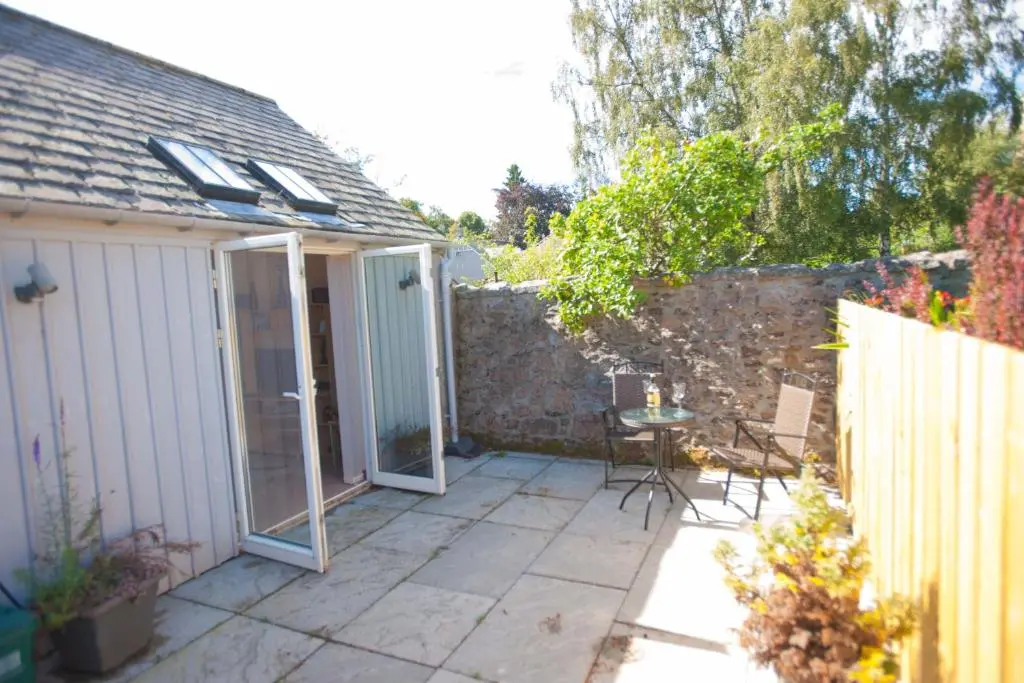 a patio with a door and a stone wall at Glenernan Self Catering Cottages in Ballater