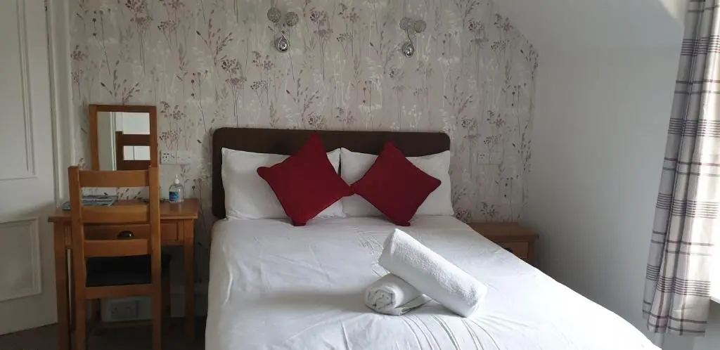 a bed with red pillows and a stuffed animal on it at Dunskaith Villa in Inverness