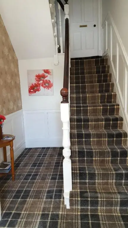a hallway with a staircase with a carpeted floor at Dunskaith Villa in Inverness