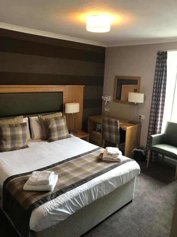 a hotel room with a bed and a chair at Buchan Hotel in Ellon