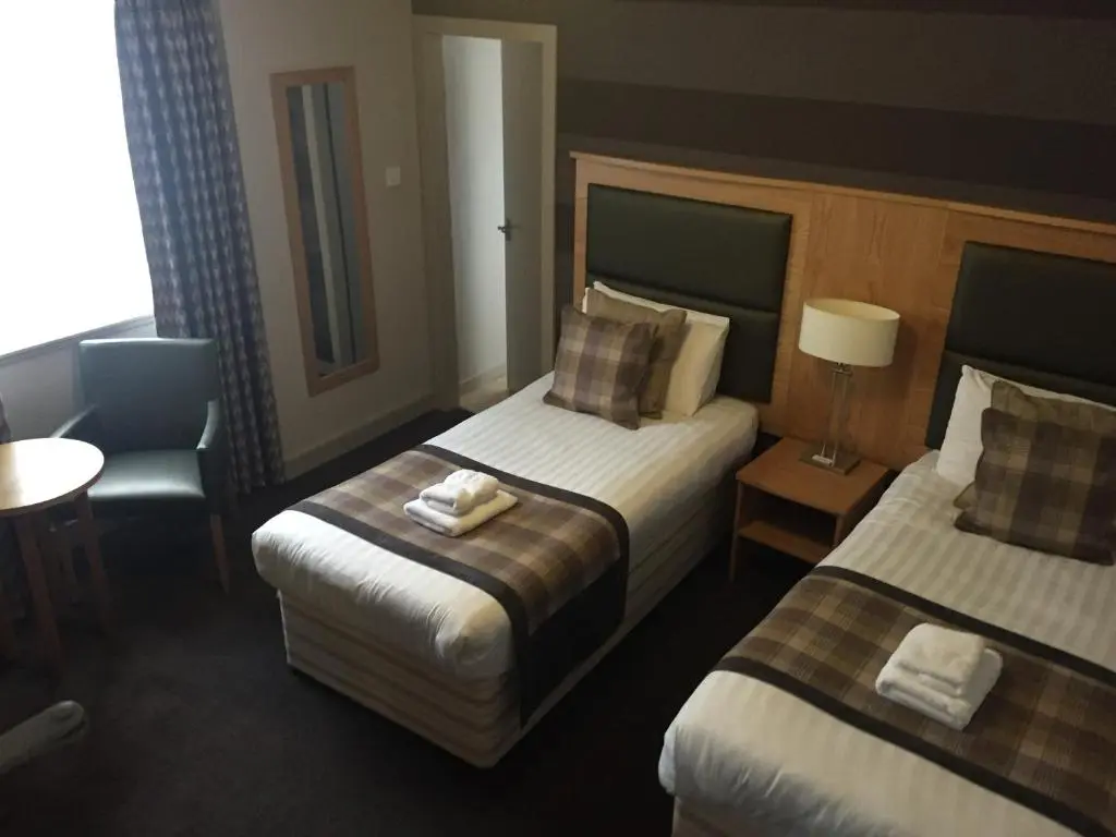 a hotel room with two beds and a table and chair at Buchan Hotel in Ellon