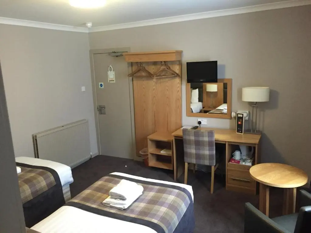 a hotel room with two beds and a desk at Buchan Hotel in Ellon